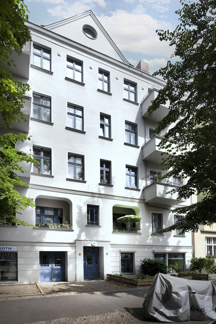 Altbau mit weißer Fassade und Balkonen